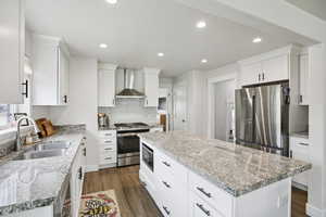 Kitchen featuring dark wood-style floors, stainless steel appliances, white cabinets, a center island, and recessed lighting