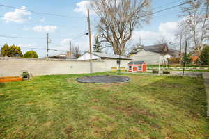 Fenced backyard featuring an outdoor structure and a trampoline
