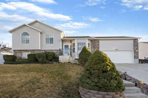 Split level home with brick siding, concrete driveway, a front yard, and an attached garage