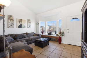 Living area featuring light tile patterned floors and lofted ceiling