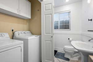 Half bathroom with a wainscoted wall, light tile patterned floors, and washing machine and dryer