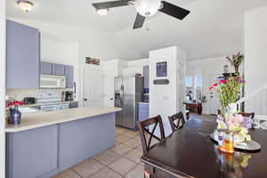Kitchen with white appliances, light tile patterned floors, light countertops, a peninsula, and a ceiling fan