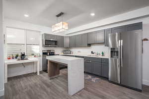 Kitchen featuring stainless steel appliances, gray cabinetry, pendant lighting, and dark wood-style flooring