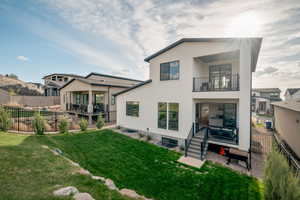 Rear view of property featuring a fenced backyard, stucco siding, a balcony, and a patio