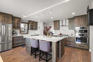 Kitchen with stainless steel appliances, a center island, backsplash, light stone counters.