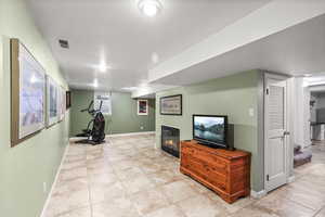 Exercise/media room featuring a glass-covered fireplace, light tile flooring, and a textured ceiling