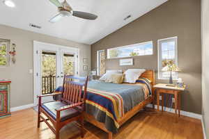 Main Bedroom featuring French doors, access to exterior deck, vaulted ceiling, oak wood floor, and a ceiling fan.