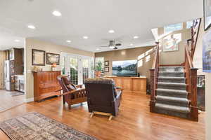 Living room with oak floors, a ceiling fan, and recessed lighting
