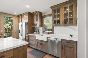 Kitchen featuring glass insert cabinets, stainless steel appliances, wood-style tile flooring, a textured ceiling, and recessed lighting