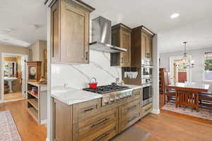 Kitchen with stainless steel appliances, tile flooring, a chandelier, wood cabinetry, and light stone countertops