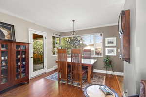 Dining area with Oak floors, suspended lighting, and ornamental molding