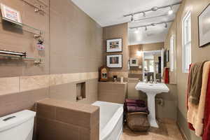 Bathroom featuring tile walls, a bath, and track lighting