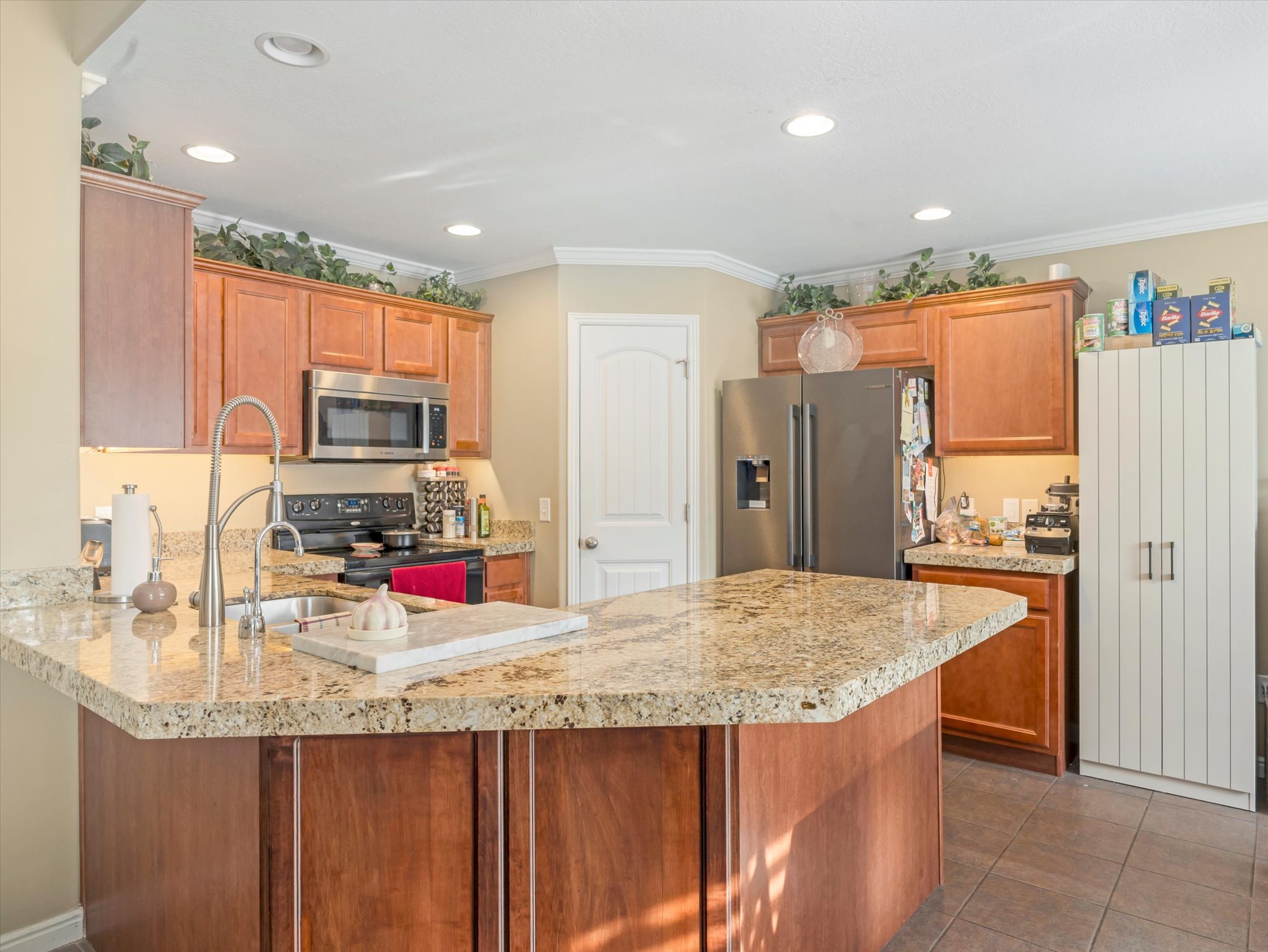 Kitchen with a peninsula, wood finish cabinets, stainless steel appliances, recessed lighting, and crown molding