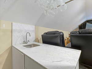 Bar with white cabinets and light stone countertops