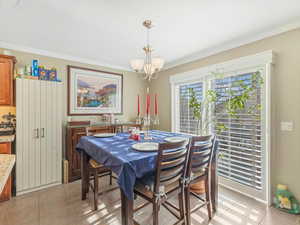 Dining room with light tile patterned flooring, ornamental molding, and suspended lighting