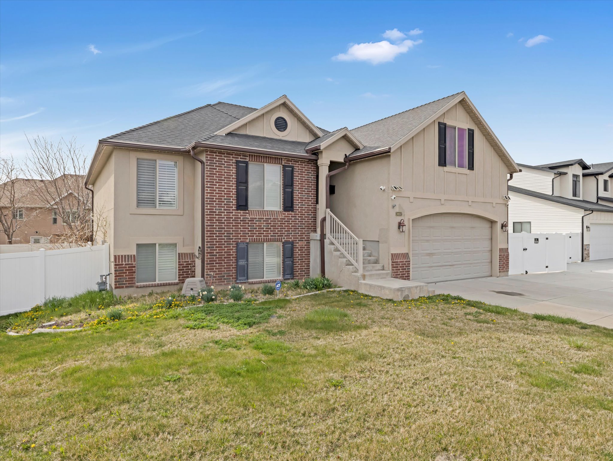 Raised ranch featuring brick siding, an attached garage, roof with shingles, concrete driveway, and board and batten siding