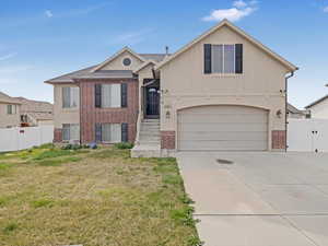 View of front of property featuring brick siding, a gate, concrete driveway, board and batten siding, and a garage