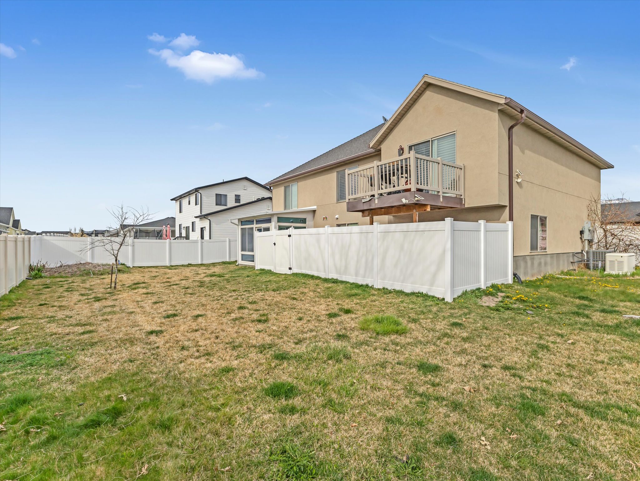 Back of house with stucco siding, a fenced backyard, and a balcony