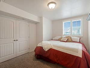 Carpeted bedroom featuring a textured ceiling and a closet