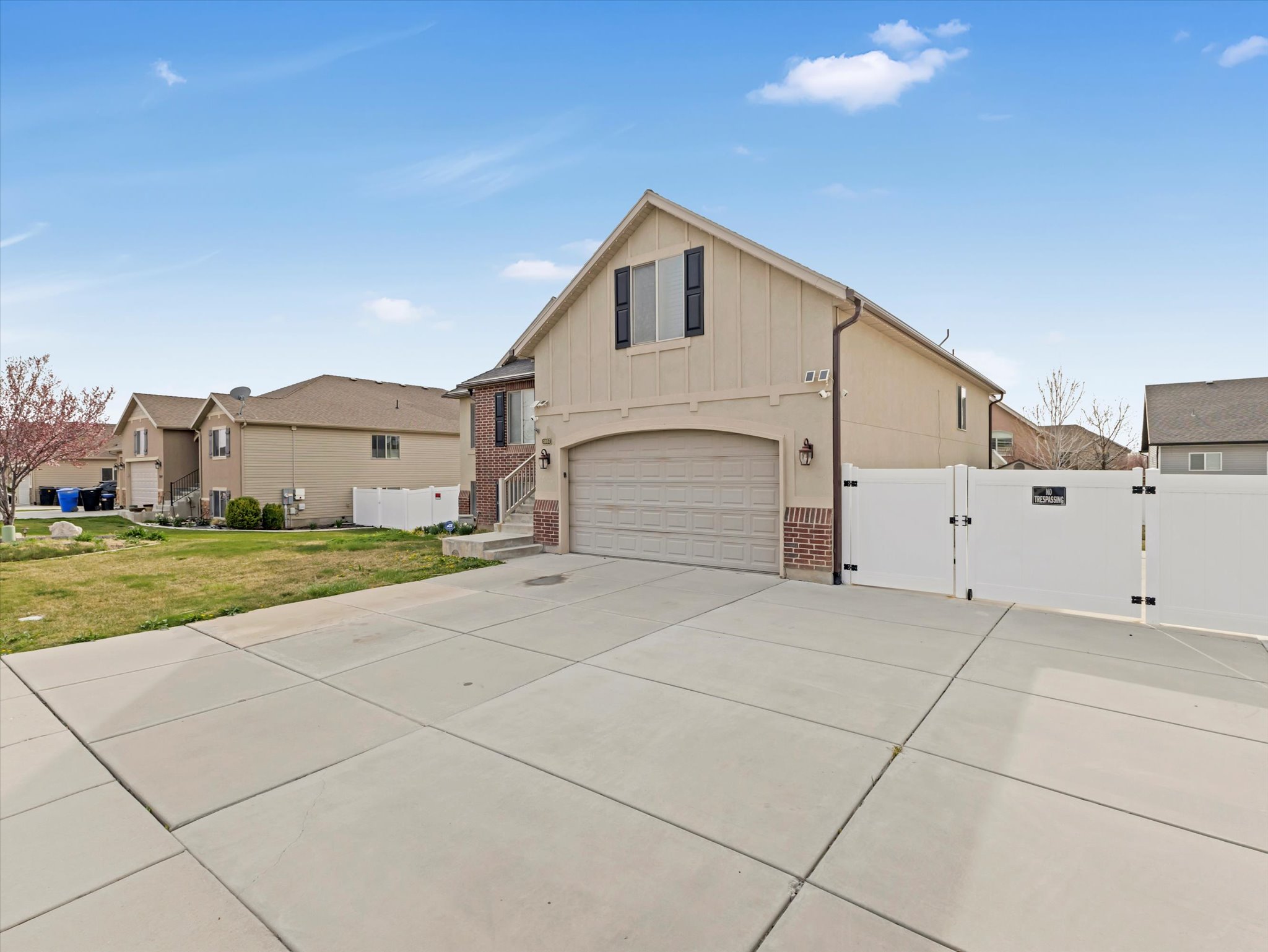 View of front of house featuring a gate, a garage, driveway, brick siding, and board and batten siding