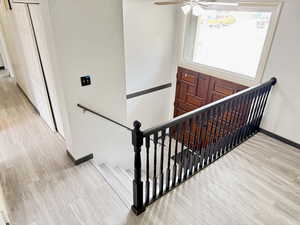 Stairs featuring wood finished floors and a ceiling fan