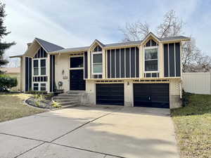 View of front of property featuring a garage, driveway, brick siding, and roof with shingles
