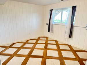 Unfurnished room featuring wooden walls