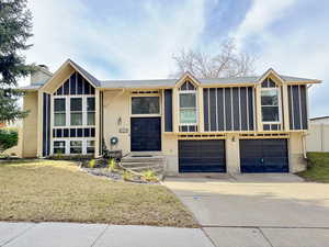 View of front of house with a front lawn, a garage, concrete driveway, brick siding, and a shingled roof