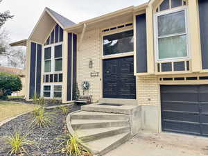 Doorway to property with brick siding and a garage