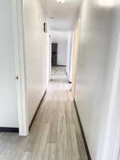 Hall with light wood-style flooring and a textured ceiling