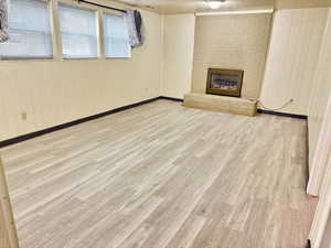 Unfurnished living room with a fireplace, wood walls, and light wood-type flooring