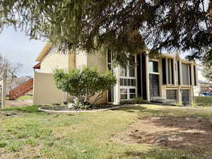 Rear view of property featuring brick siding and a lawn