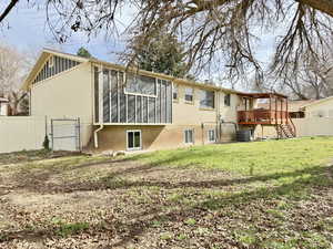 Back of house with a gate, brick siding, and a sunroom