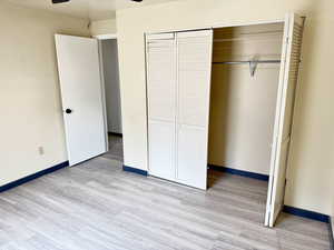 Unfurnished bedroom with a ceiling fan, a closet, and light wood finished floors