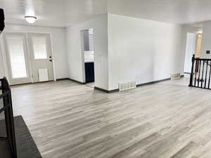 Unfurnished living room with light wood-style flooring and a textured ceiling