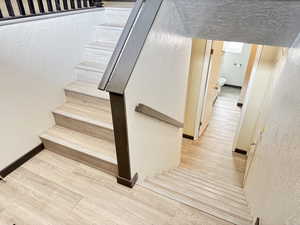 Stairway featuring a textured wall and wood finished floors