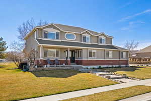 View of front of property featuring a porch, brick and stucco exterior, a front yard with walkway and flower beds