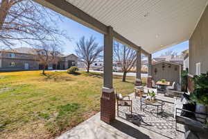 View of green lawn, mature trees, and spacious covered patio area with outdoor lighting