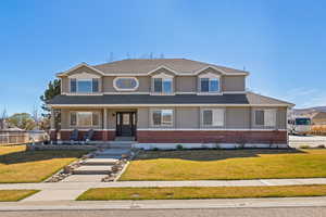 View of front of property featuring a porch, brick and stucco exterior, a front yard with walkway and flower beds