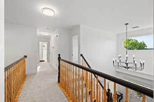 Catwalk style hallway with views of foyer and living room, featuring plush carpet and natural light
