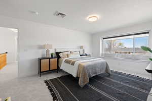 Primary bedroom with large windows, custom roller shades, light paint and plush carpet
