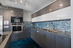 ADU Kitchen with modern cabinetry, colored backsplash tile, stainless steel appliances and quartz counters