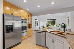 Open concept living space featuring kitchen and spacious dining area, light, tile flooring, can lighting, dark quartz countertops and stainless steel appliances