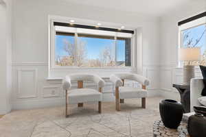 Front living room with decorative paneled wainscot, large windows, carpet flooring and light paint