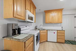 Basement second kitchen with light wood cabinetry, white appliances and separate entrance