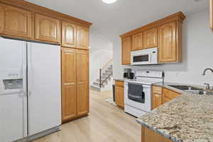 Basement second kitchen with light wood cabinetry, white appliances and separate entrance