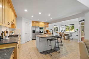 Open concept living space featuring kitchen and spacious dining area, light, tile flooring, can lighting, dark quartz countertops and stainless steel appliances