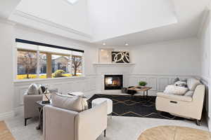 Living room space featuring decorative paneling, large windows, 2-story ceiling, plush carpet and a fireplace