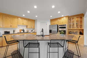 Large kitchen featuring light wood cabinetry, can lighting, corner pantry, spacious island, quartz countertops and stainless steel appliances