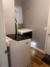 Laundry area with baseboards and dark wood finished floors